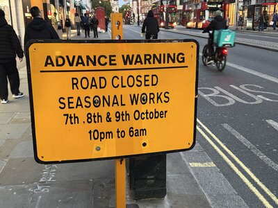 Yellow warning sign with black text ROAD CLOSED SEASONAL WORKS 7th 8th 9th October 10pm to 6am, traffic management notice for construction