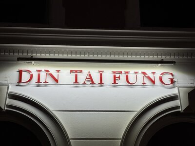 DIN TAI FUNG restaurant sign in large red capital letters on white facade, Art Deco styling, upscale Asian dining establishment
