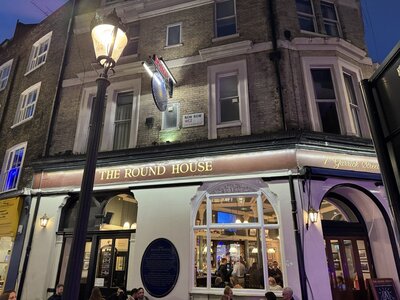 Round House pub exterior at night with illuminated facade, New Row WC2 Covent Garden, traditional London public house, street lamp, warm interior glow